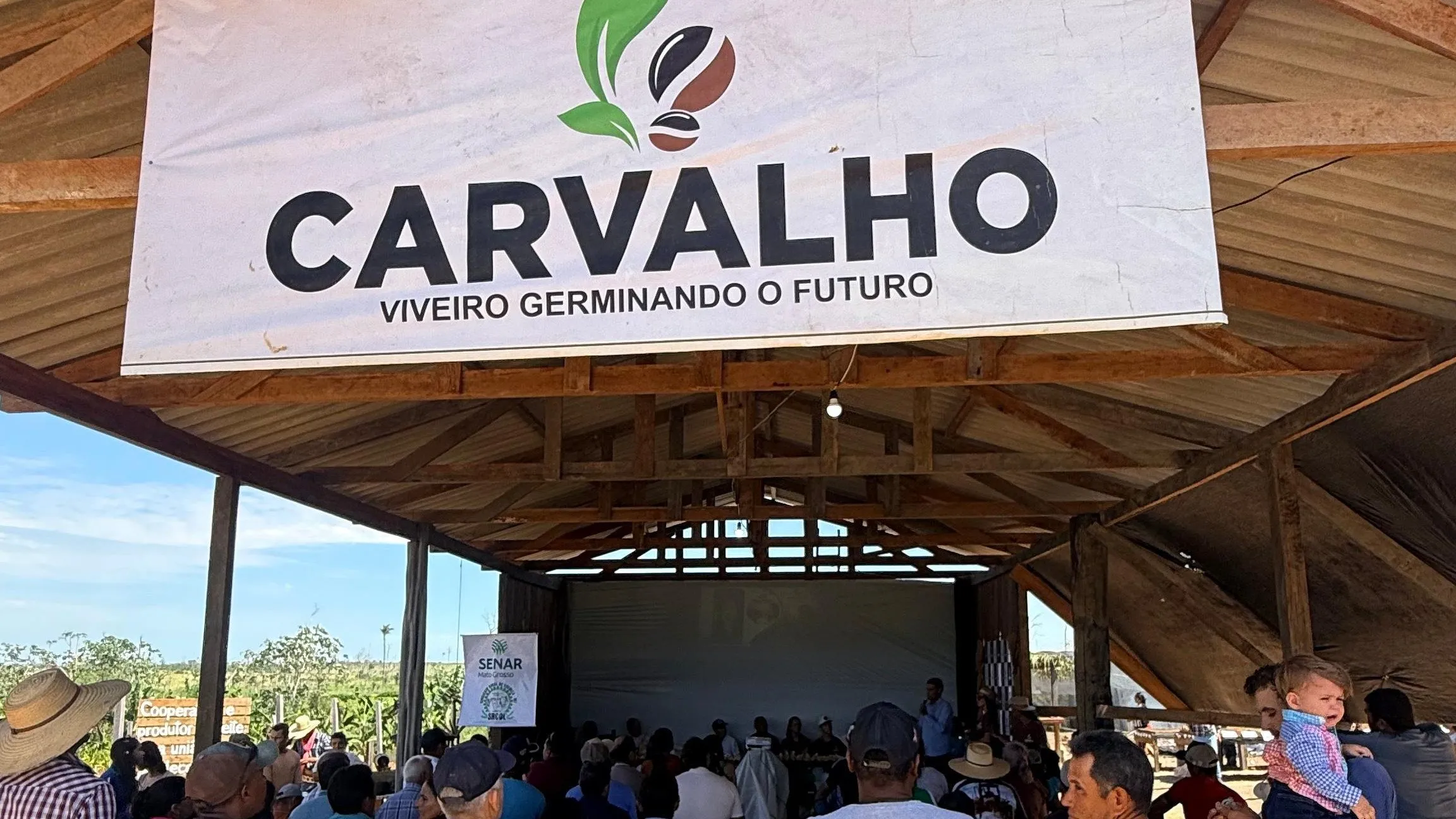 A Carvalho banner on a timber shed under construction at the cooperative's nursery, with members gathered around it.