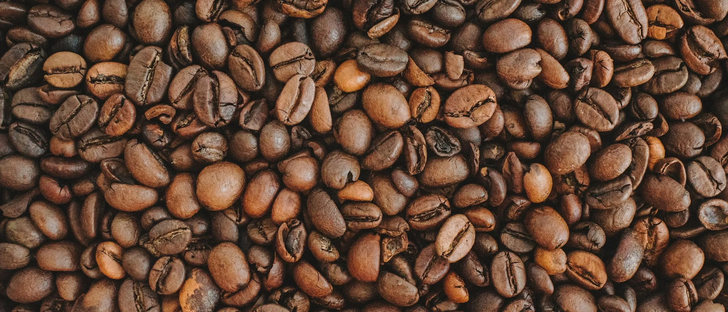 Roasted coffee beans spread across a wooden surface.